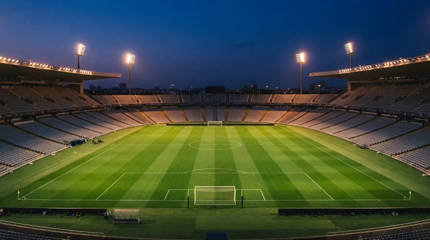 An empty football stadium with floodlight masts at dusk