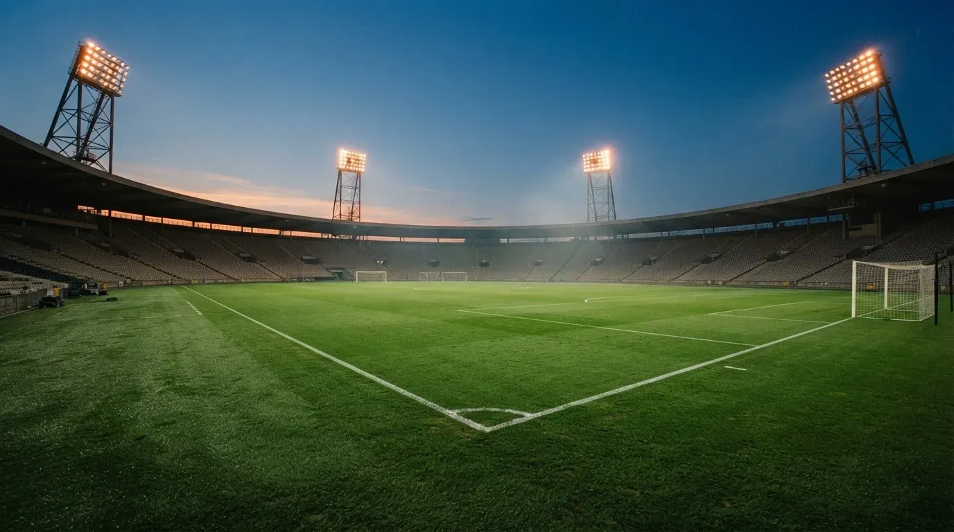 An empty football stadium with floodlight masts at dusk