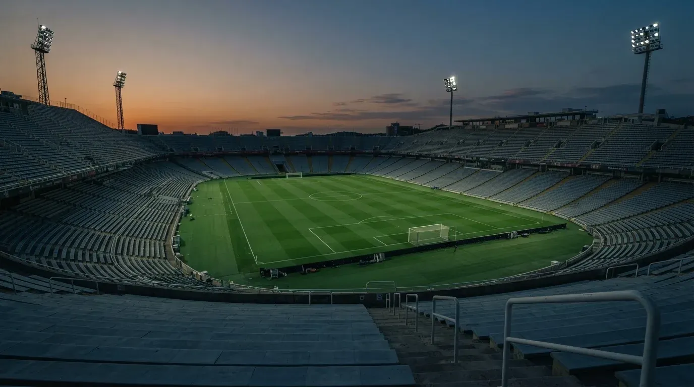 An empty football stadium with floodlight masts at dusk