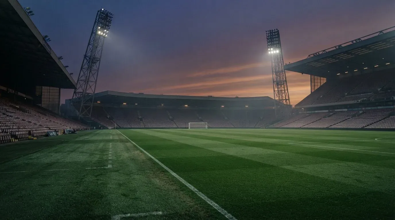 An empty football stadium with floodlight masts at dusk