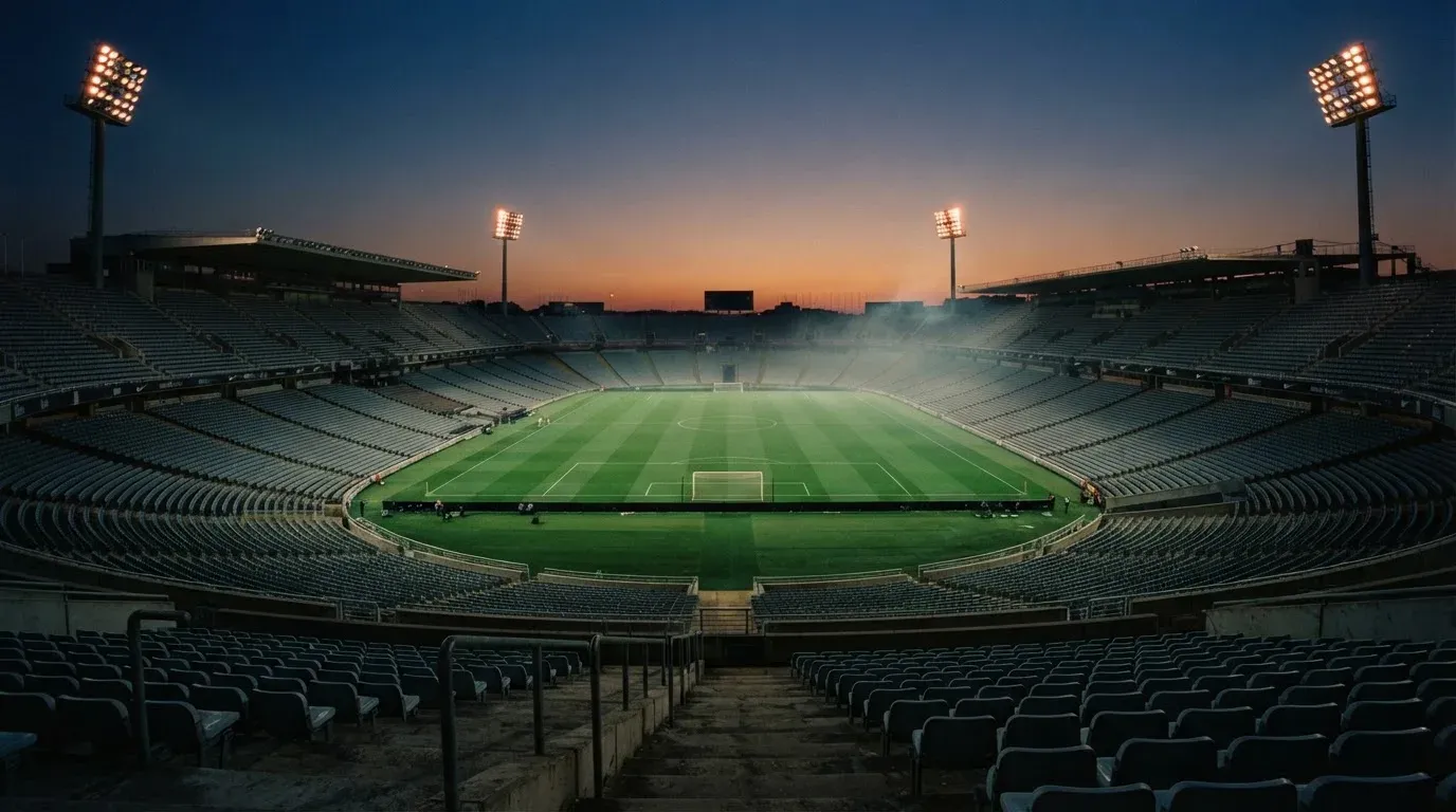 An empty football stadium with floodlight masts at dusk