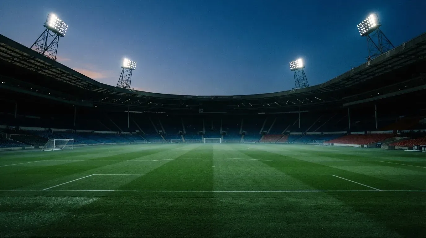 An empty football stadium with floodlight masts at dusk