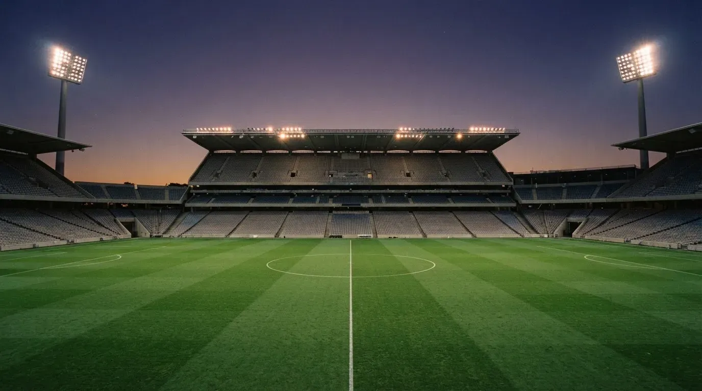 An empty football stadium with floodlight masts at dusk