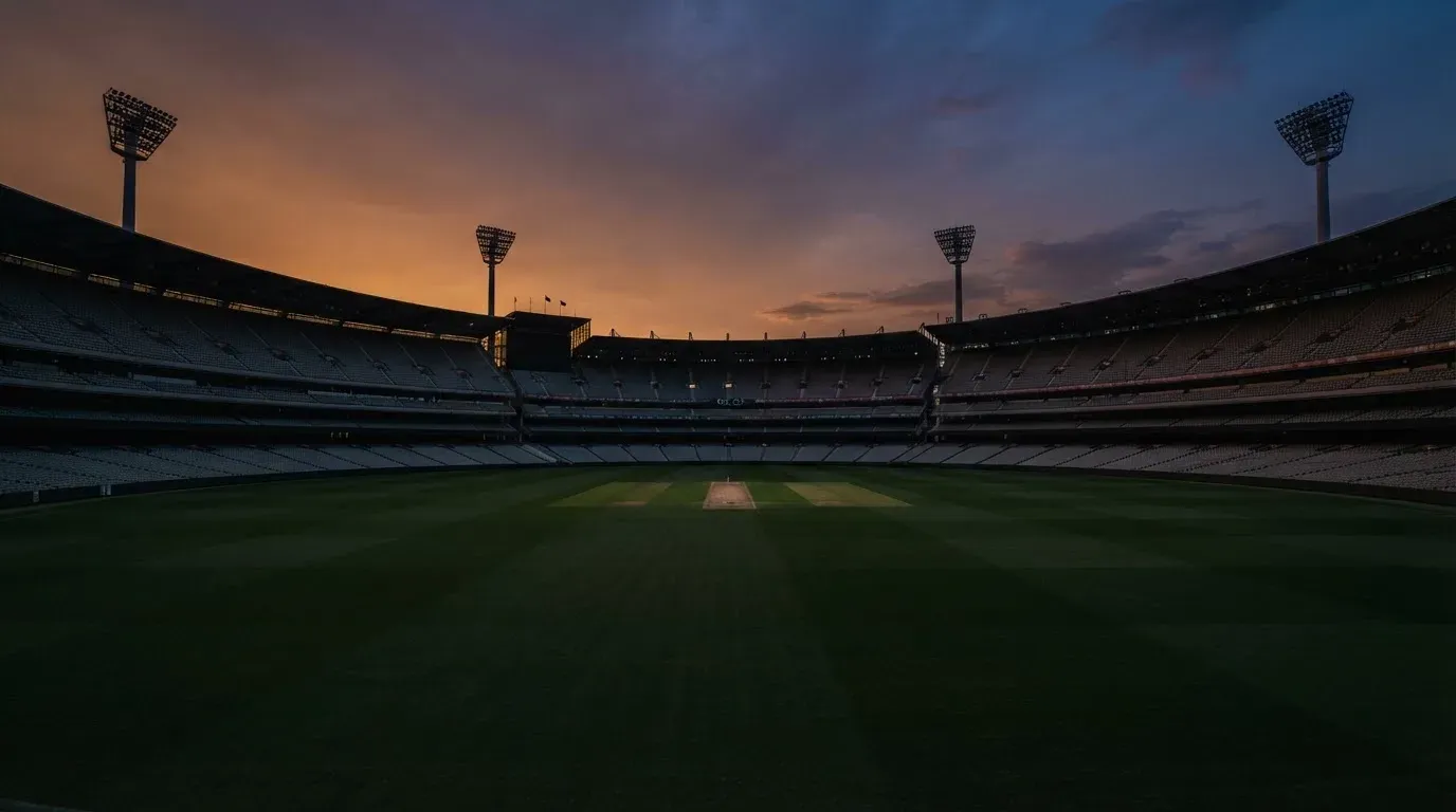 An empty football stadium with floodlight masts at dusk