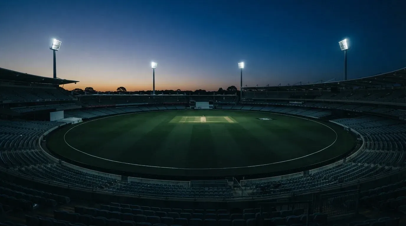An empty football stadium with floodlight masts at dusk