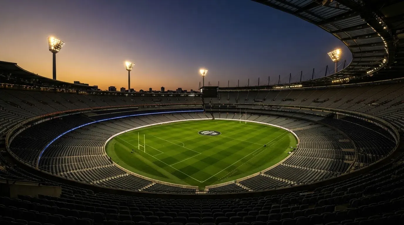 An empty football stadium with floodlight masts at dusk