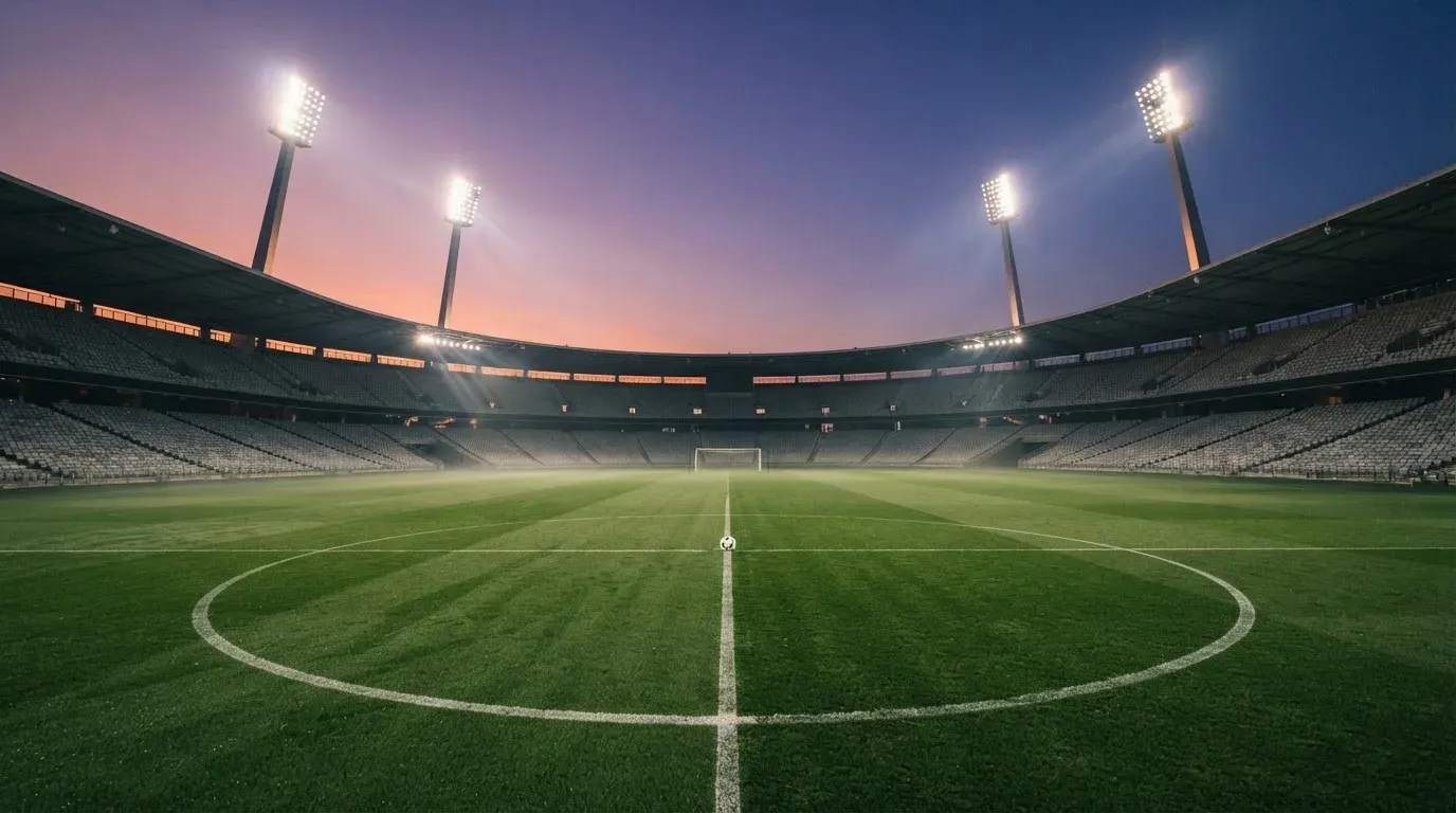An empty football stadium with floodlight masts at dusk