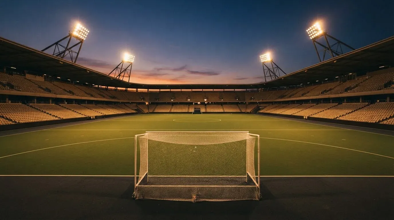 An empty football stadium with floodlight masts at dusk