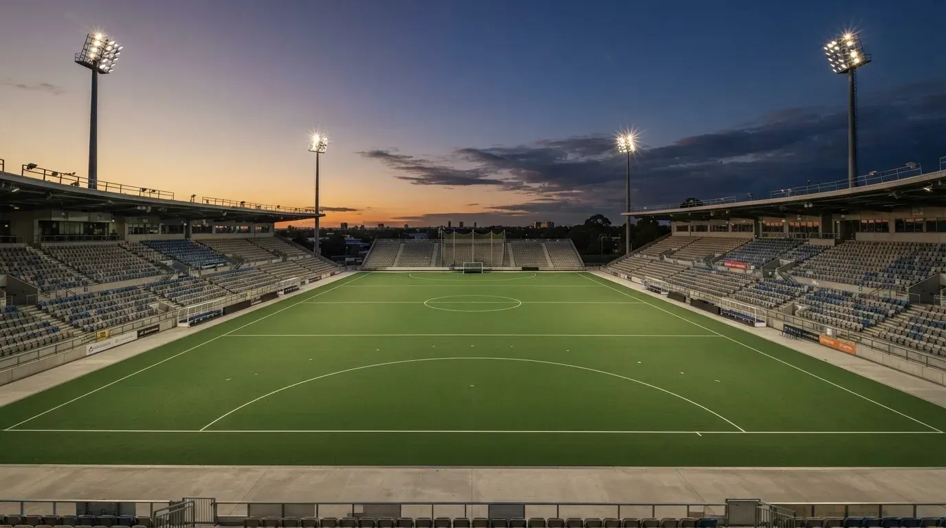 An empty football stadium with floodlight masts at dusk