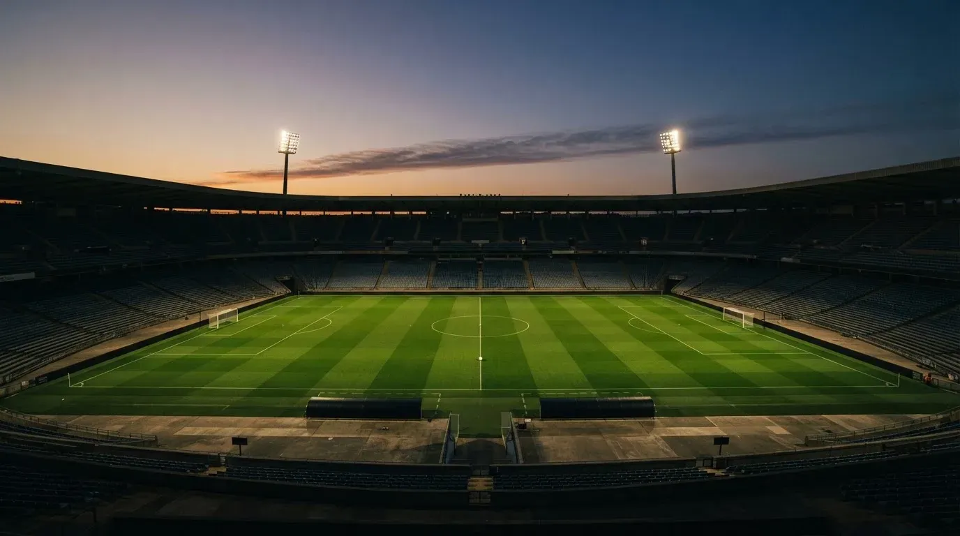 An empty football stadium with floodlight masts at dusk