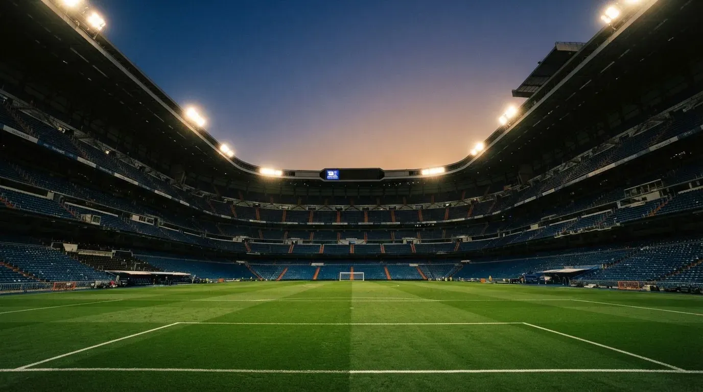 An empty football stadium with floodlight masts at dusk
