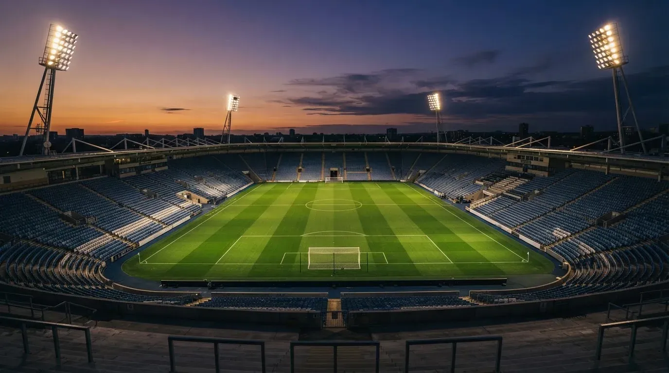 An empty football stadium with floodlight masts at dusk