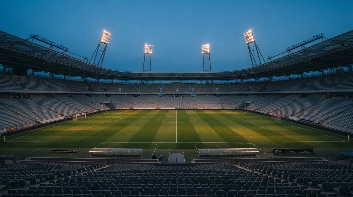 An empty football stadium with floodlight masts at dusk