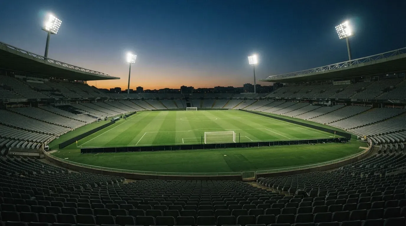 An empty football stadium with floodlight masts at dusk