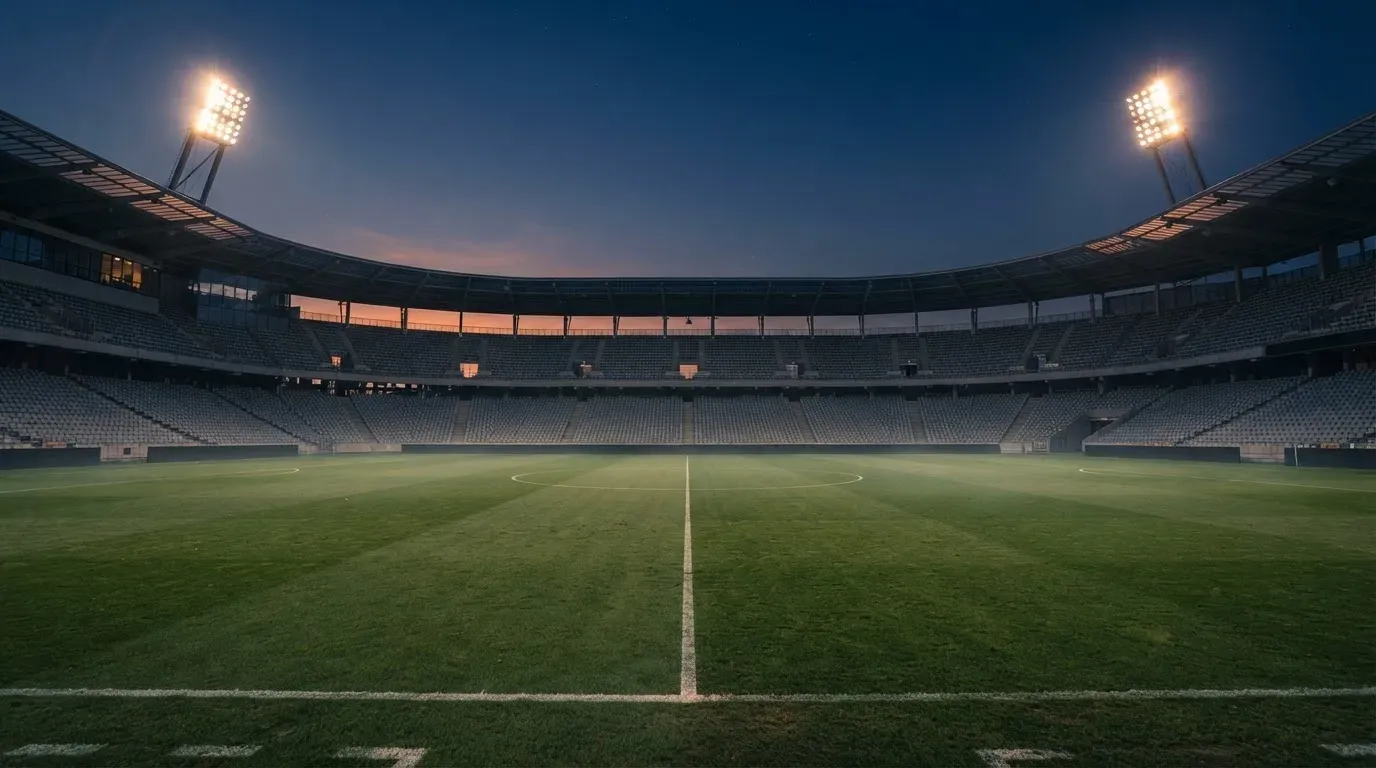 An empty football stadium with floodlight masts at dusk