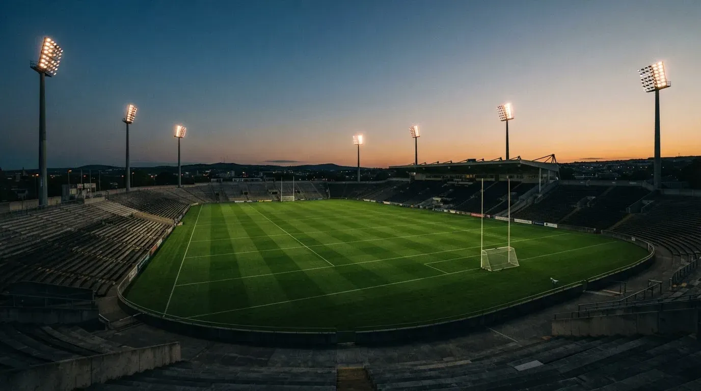 An empty football stadium with floodlight masts at dusk