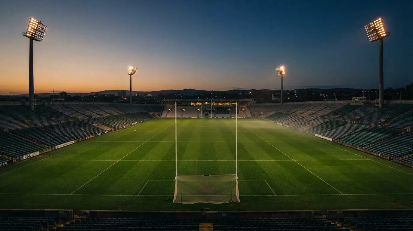 An empty football stadium with floodlight masts at dusk
