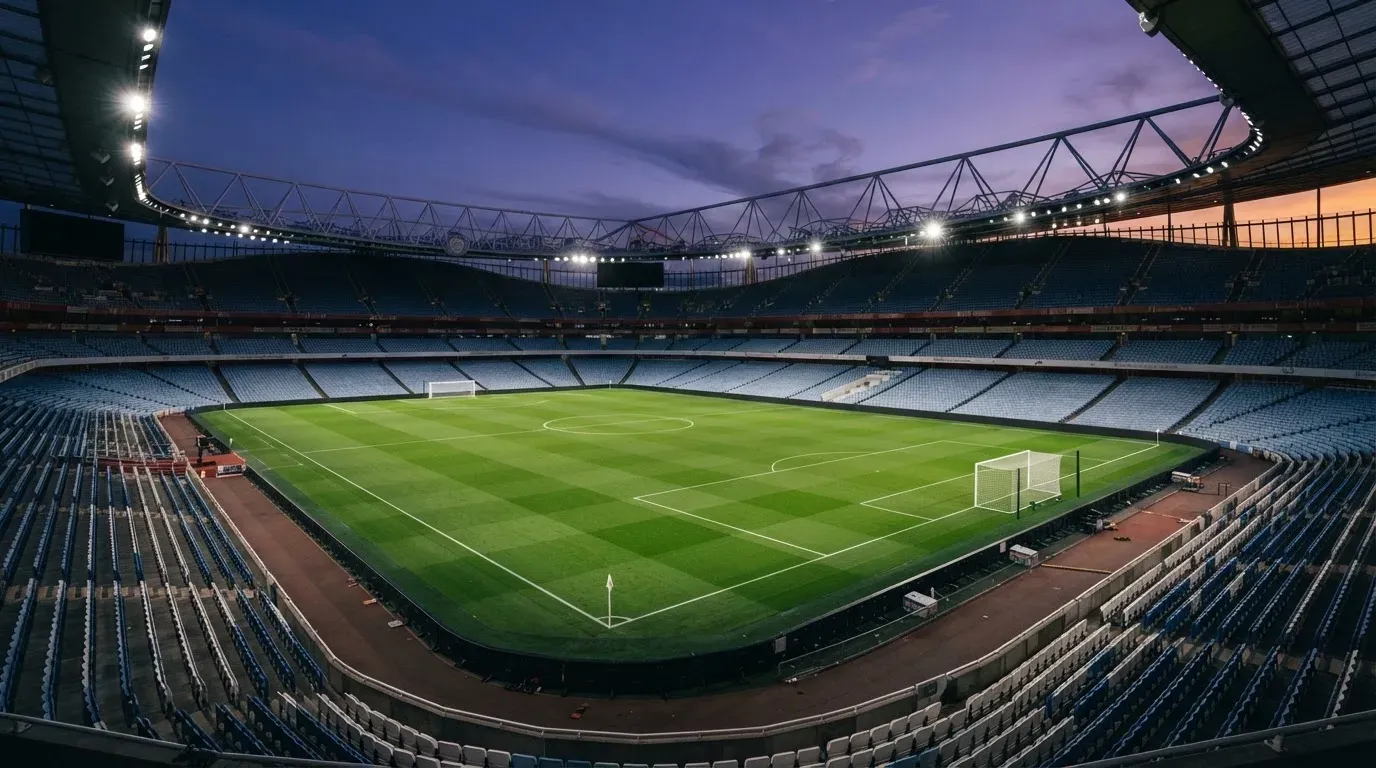 An empty football stadium with floodlight masts at dusk