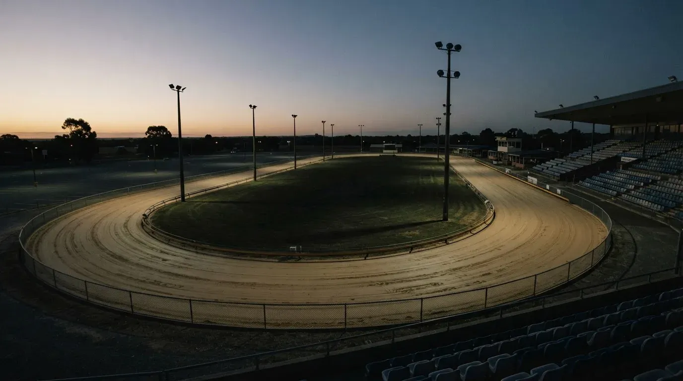 An empty football stadium with floodlight masts at dusk