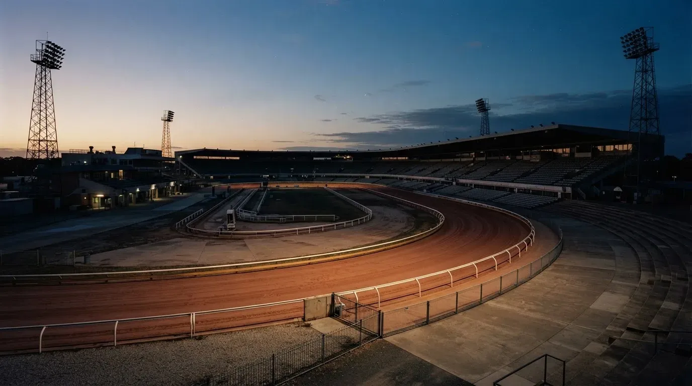 An empty football stadium with floodlight masts at dusk
