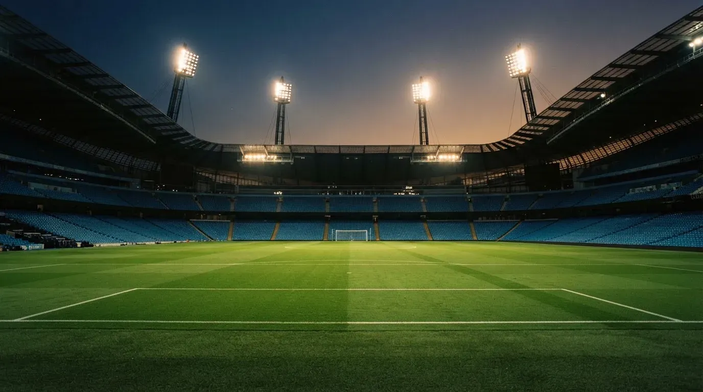 An empty football stadium with floodlight masts at dusk