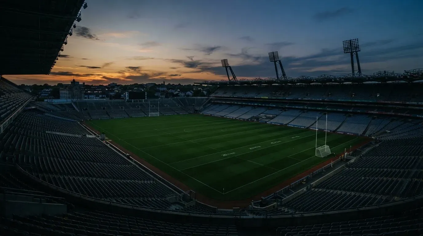 An empty football stadium with floodlight masts at dusk