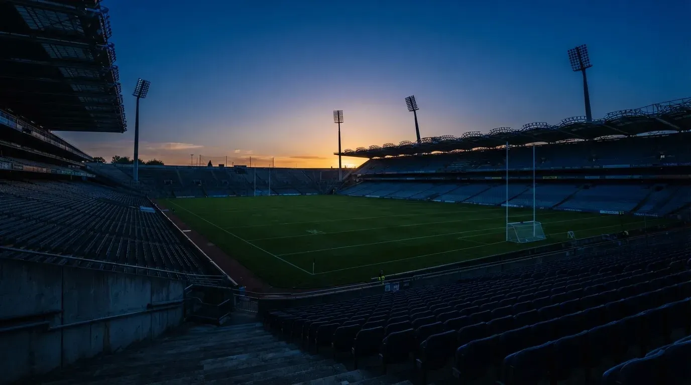 An empty football stadium with floodlight masts at dusk