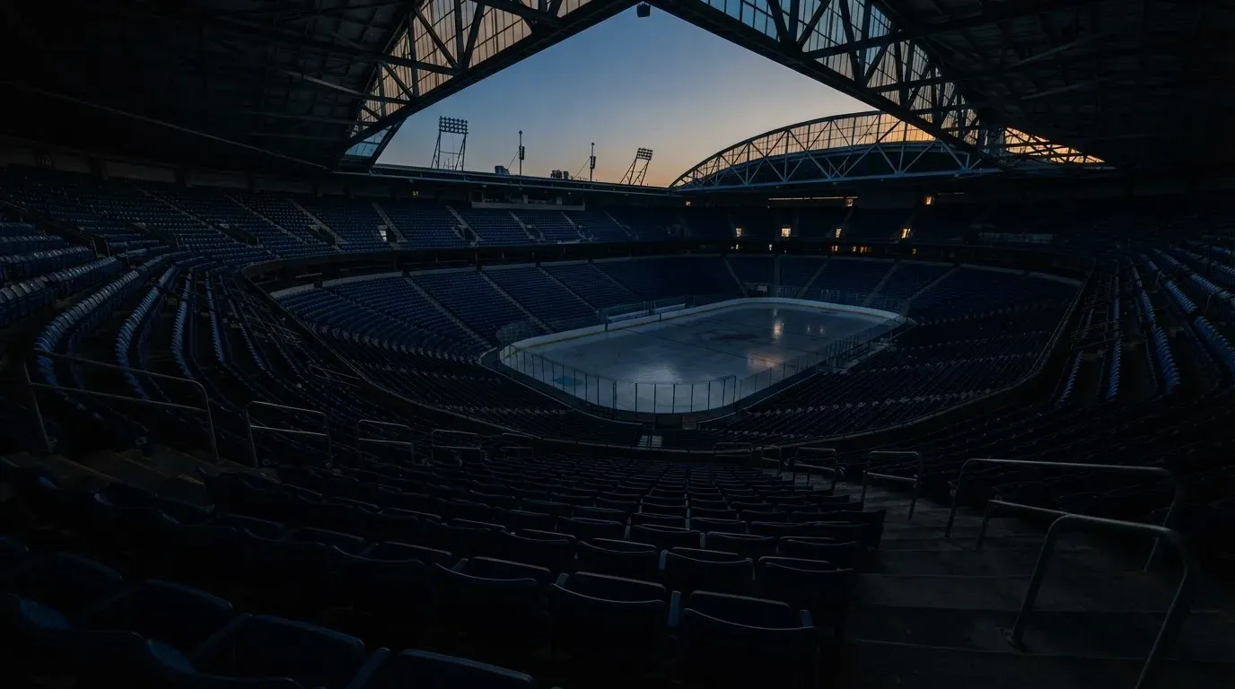 An empty football stadium with floodlight masts at dusk