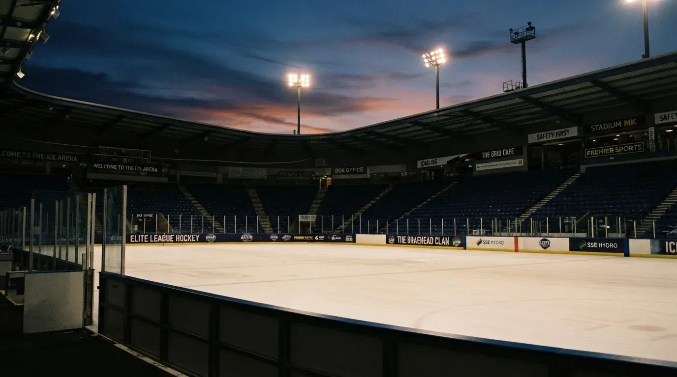 An empty football stadium with floodlight masts at dusk
