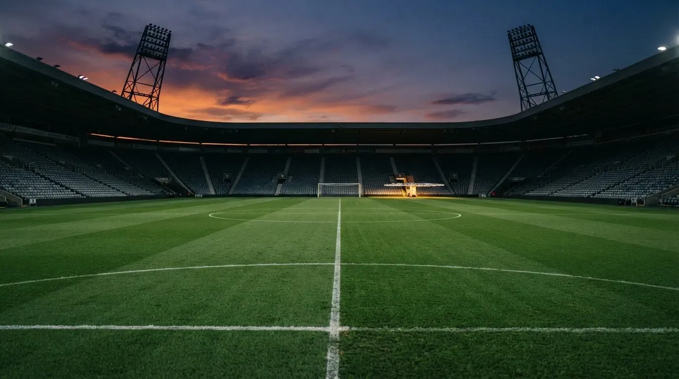 An empty football stadium with floodlight masts at dusk