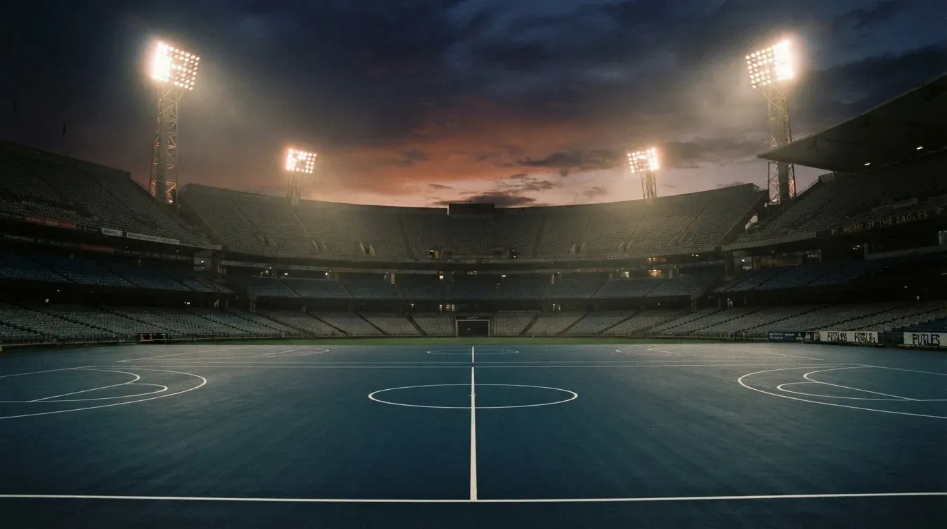 An empty football stadium with floodlight masts at dusk