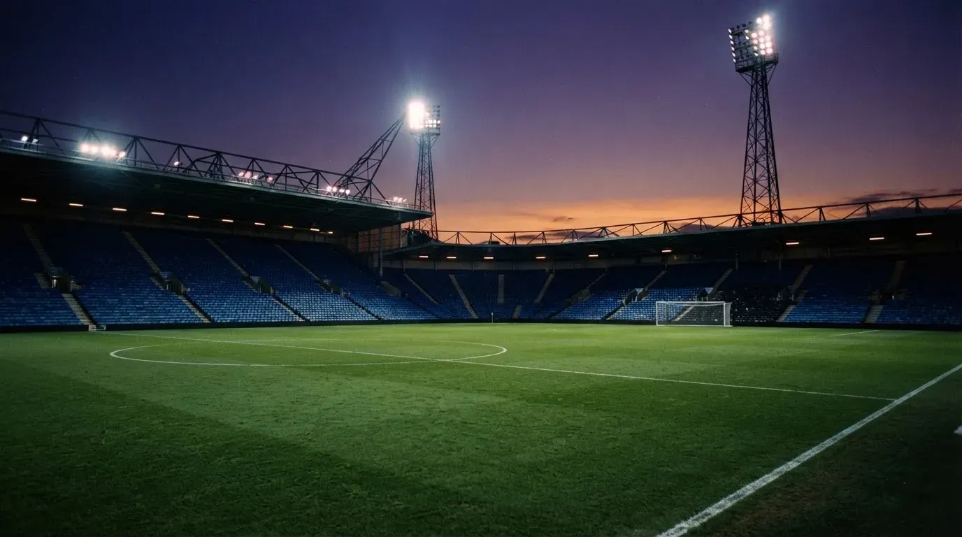 An empty football stadium with floodlight masts at dusk
