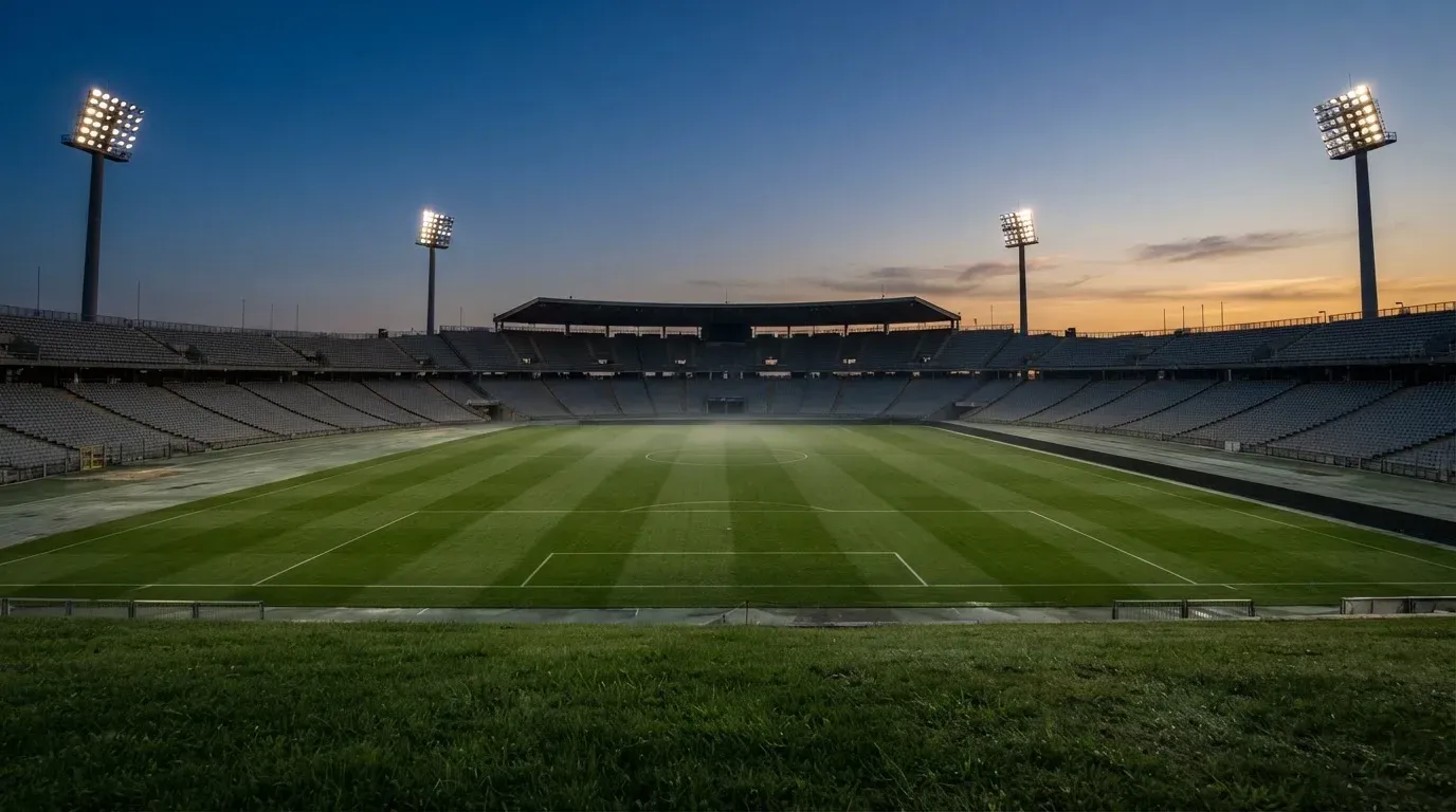 An empty football stadium with floodlight masts at dusk