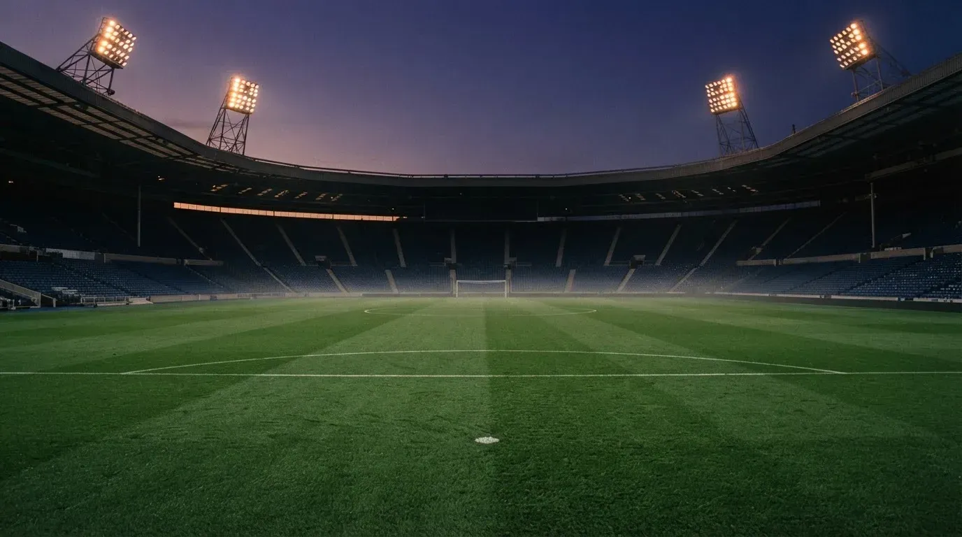 An empty football stadium with floodlight masts at dusk