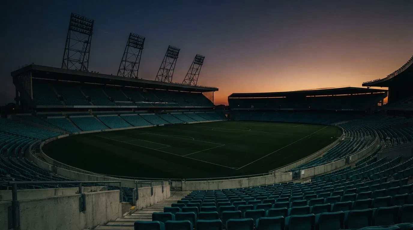 An empty football stadium with floodlight masts at dusk