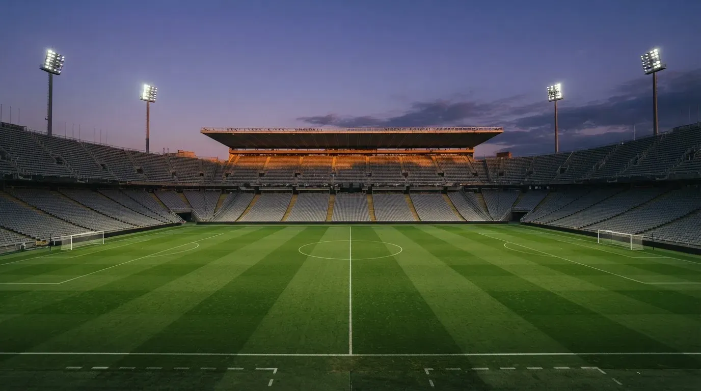 An empty football stadium with floodlight masts at dusk