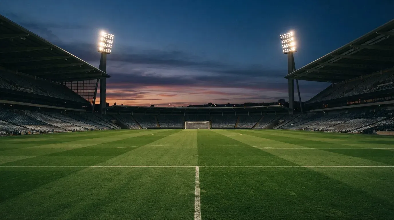 An empty football stadium with floodlight masts at dusk