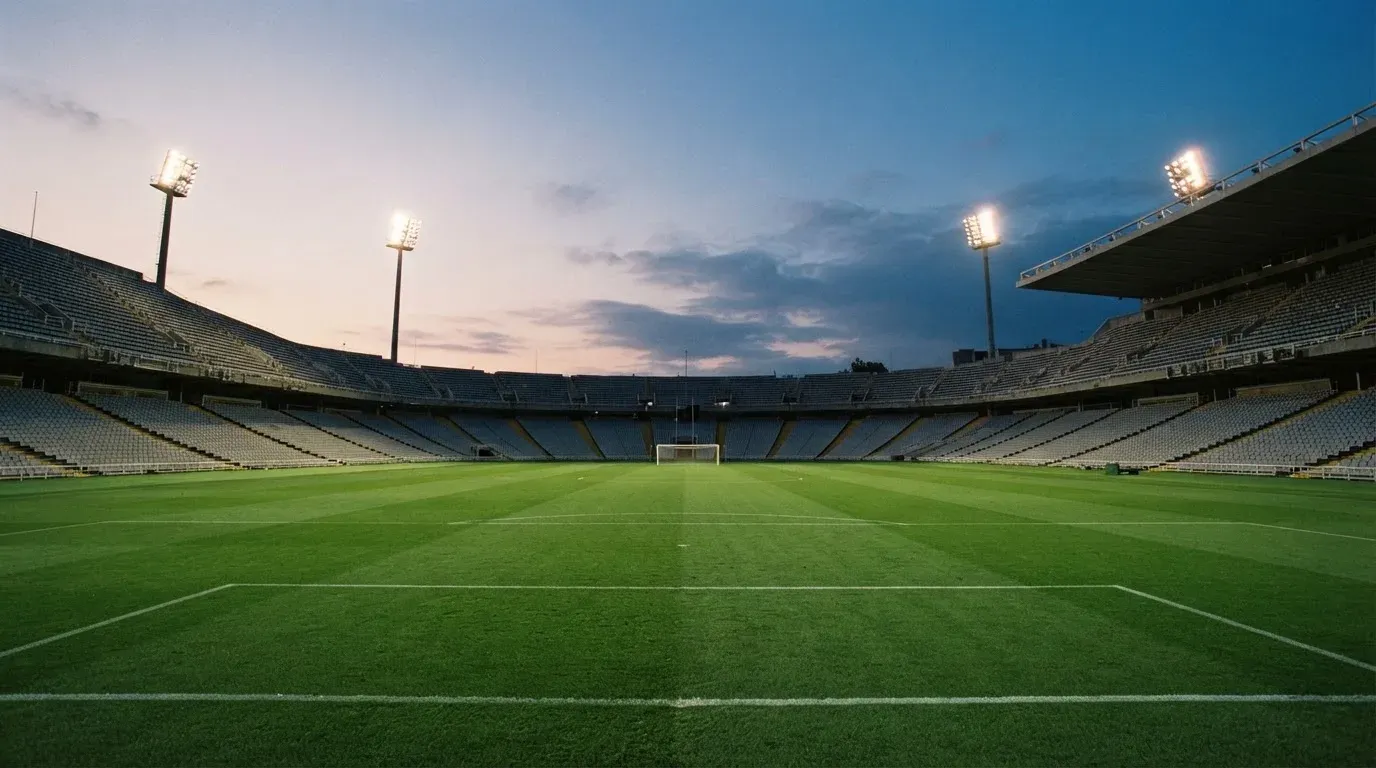An empty football stadium with floodlight masts at dusk