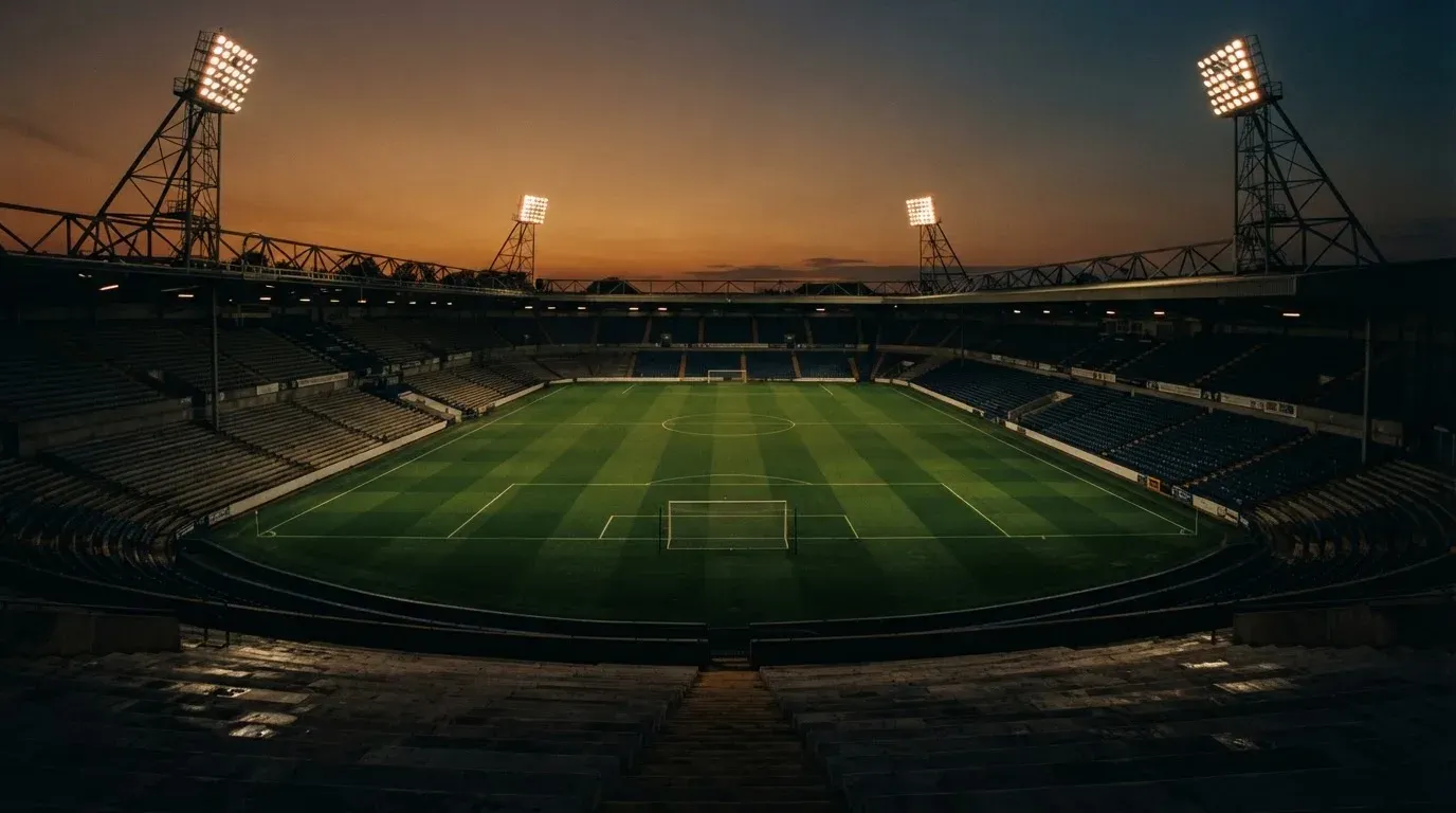 An empty football stadium with floodlight masts at dusk
