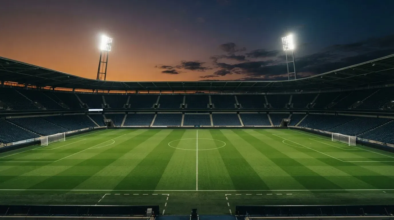 An empty football stadium with floodlight masts at dusk