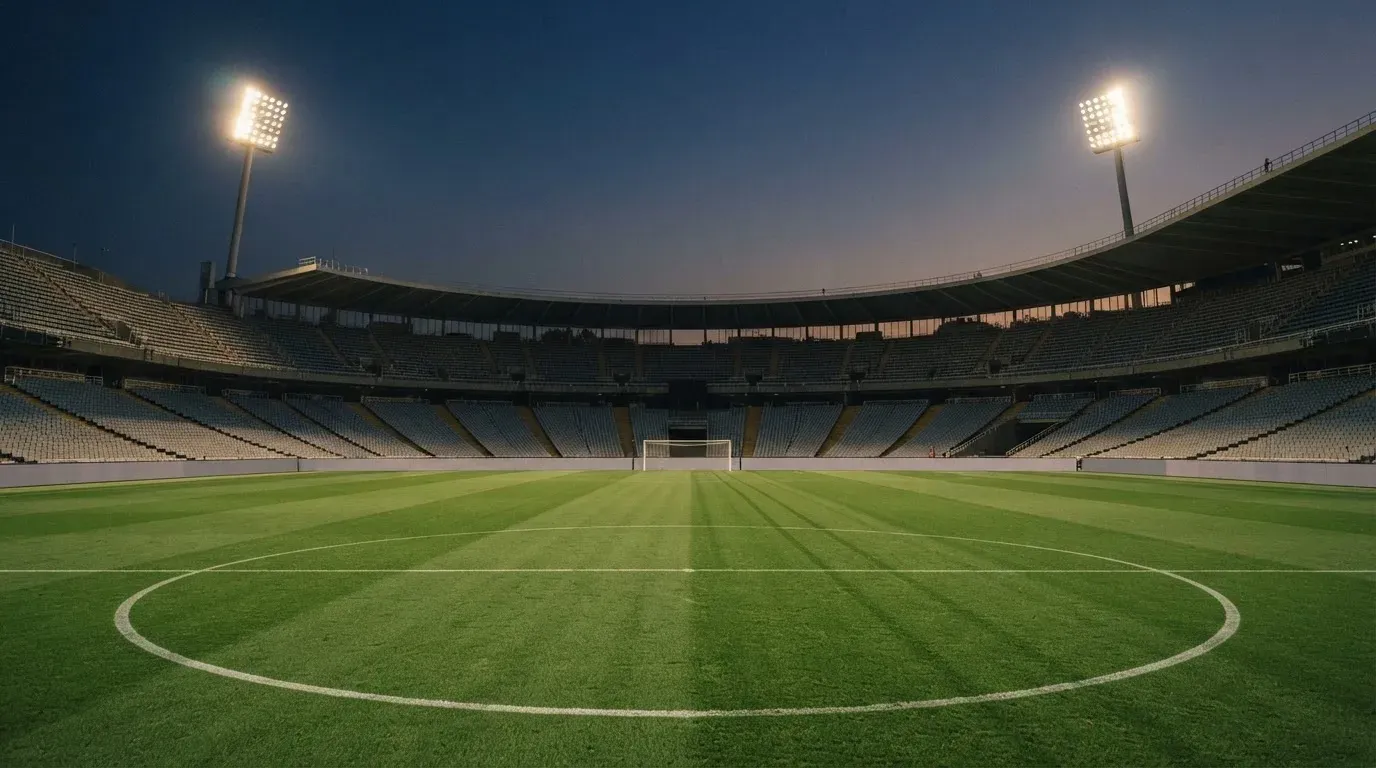 An empty football stadium with floodlight masts at dusk
