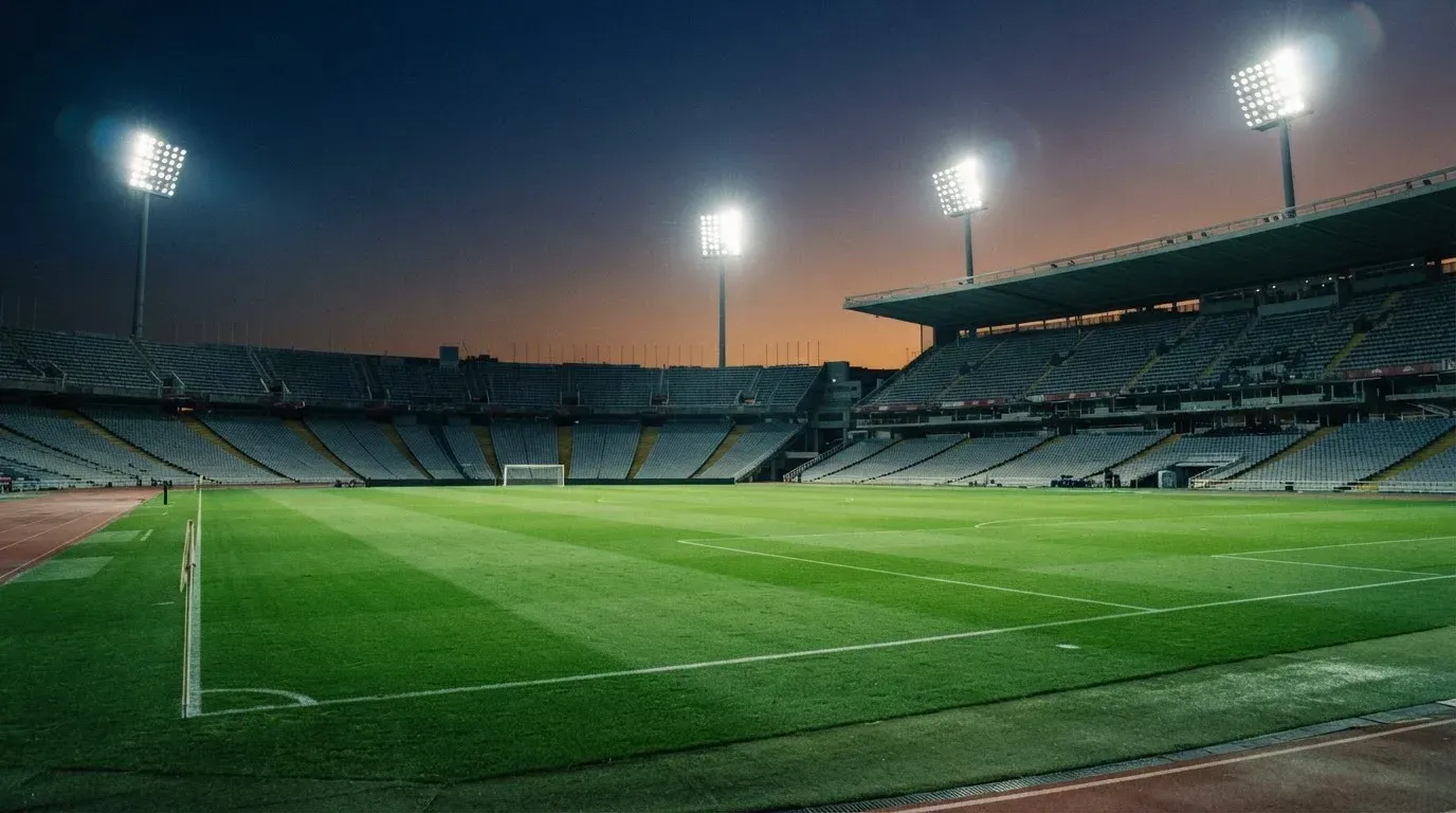 An empty football stadium with floodlight masts at dusk