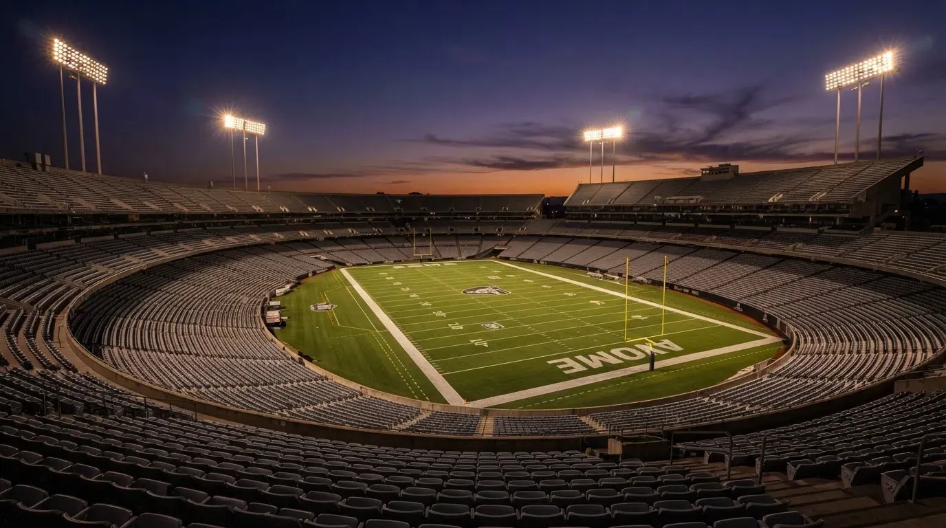 An empty football stadium with floodlight masts at dusk