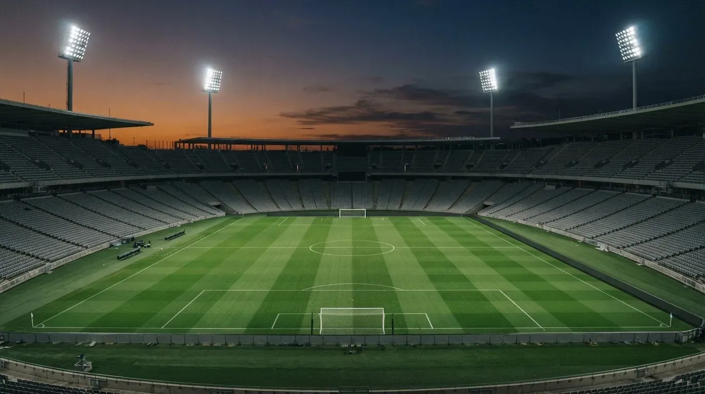 An empty football stadium with floodlight masts at dusk