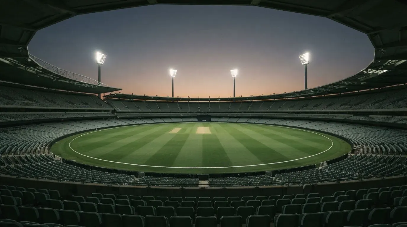 An empty football stadium with floodlight masts at dusk