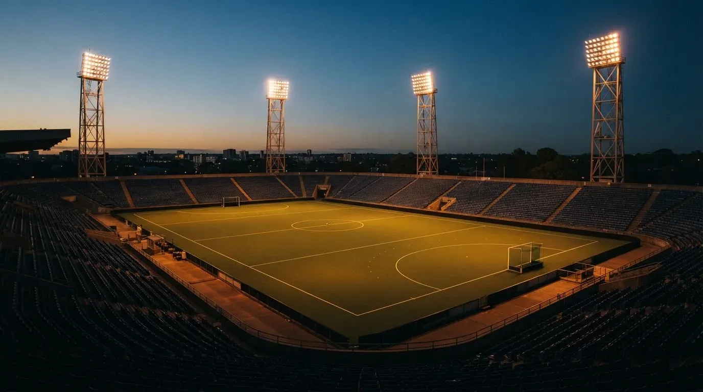 An empty football stadium with floodlight masts at dusk