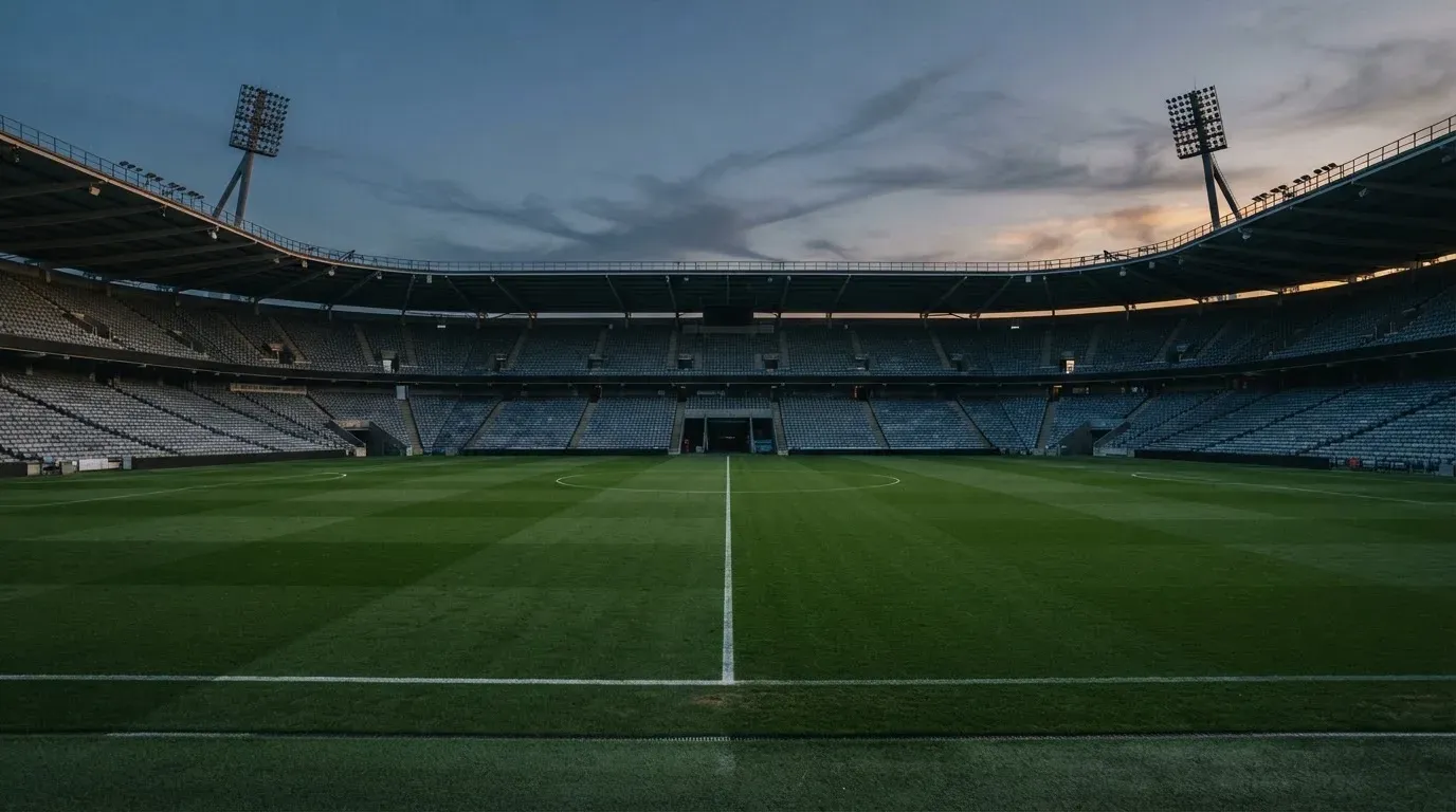 An empty football stadium with floodlight masts at dusk