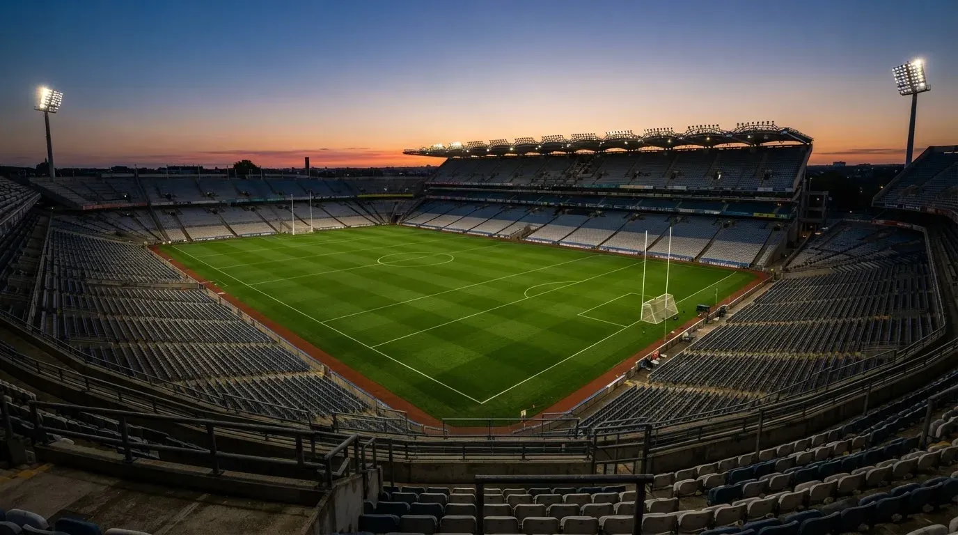 An empty football stadium with floodlight masts at dusk