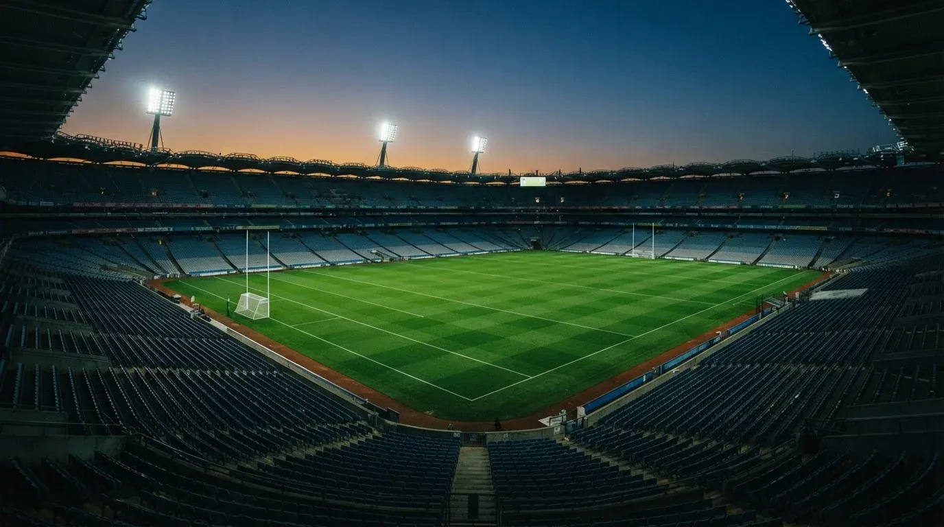 An empty football stadium with floodlight masts at dusk