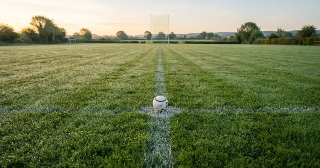 A ball on the centre spot of a grass pitch in morning light